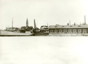 Telakka päätyi viisi vuotta myöhemmin osaksi And. Auvisen kauppahuonetta. Samalla telakan nimi vaihtui Savonlinnan Konepaja Oy:ksi. Rannassa oleva laiva on And. Auvinen Oy:n omistama s/s Tiera. Kuva 1920- ja 1930-lukujen taitteesta.