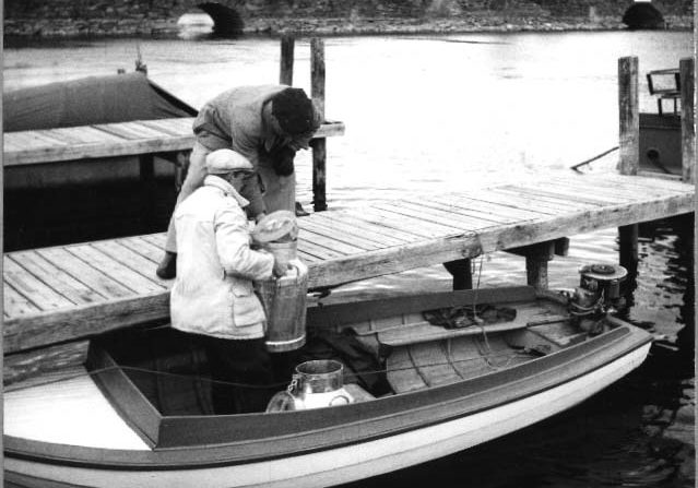 Mies ja poika lastaavat tyhjiä maitotonkkia Puistokadun laiturissa olevaan perämoottoriveneeseen 1950-luvulla. Mies ja poika lastaavat tyhjiä maitotonkkia Savonlinnan kaupungin Puistokadun laiturissa olevaan perämoottoriveneeseen 1950-luvulla.